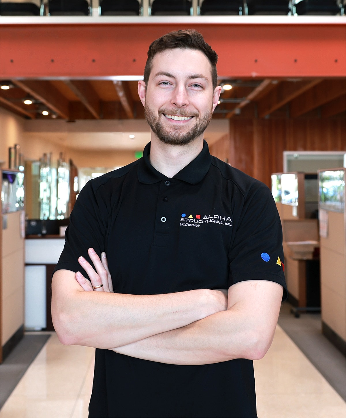Smiling man with arms crossed in office setting.