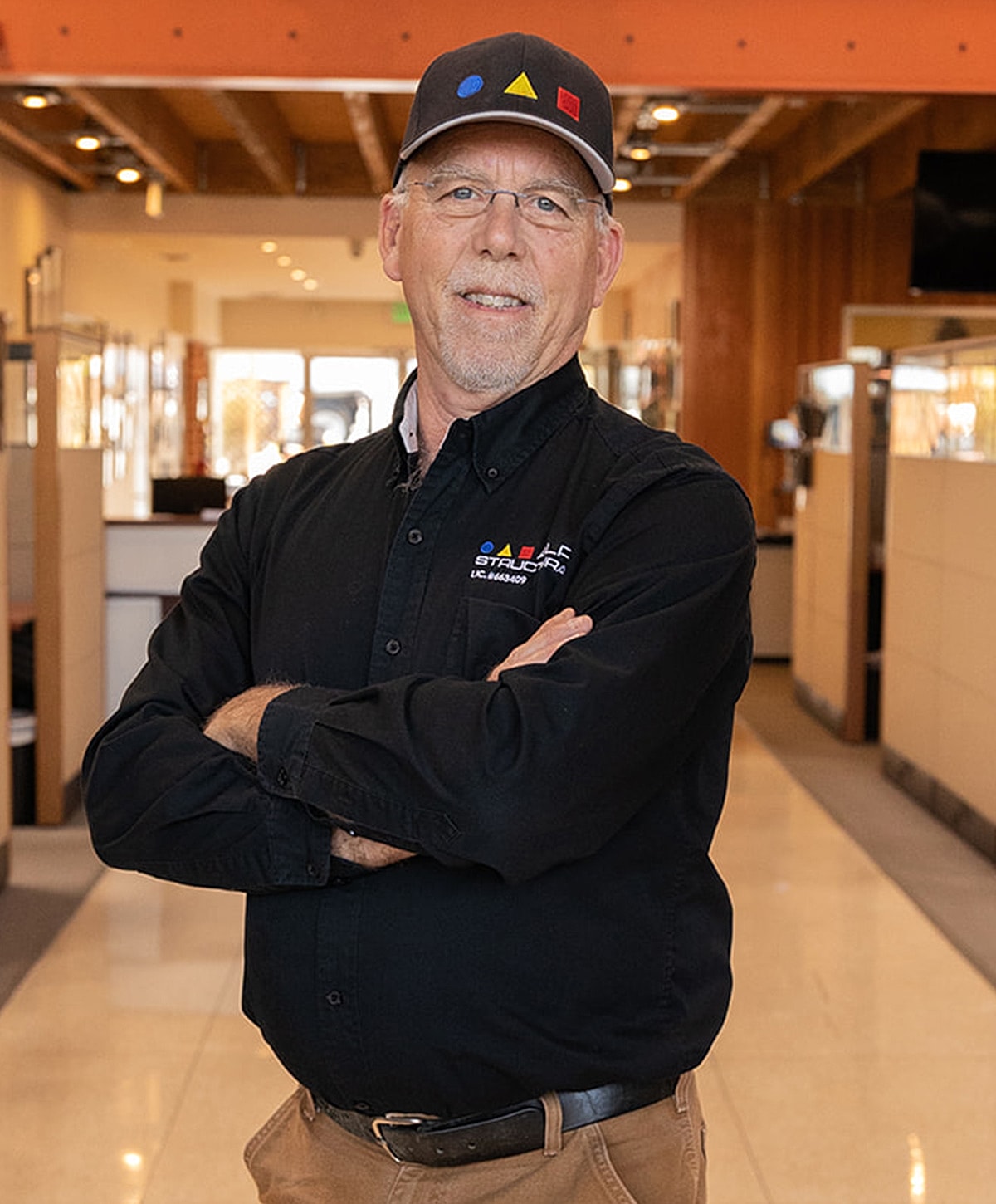 Man in a black shirt and cap, arms crossed.