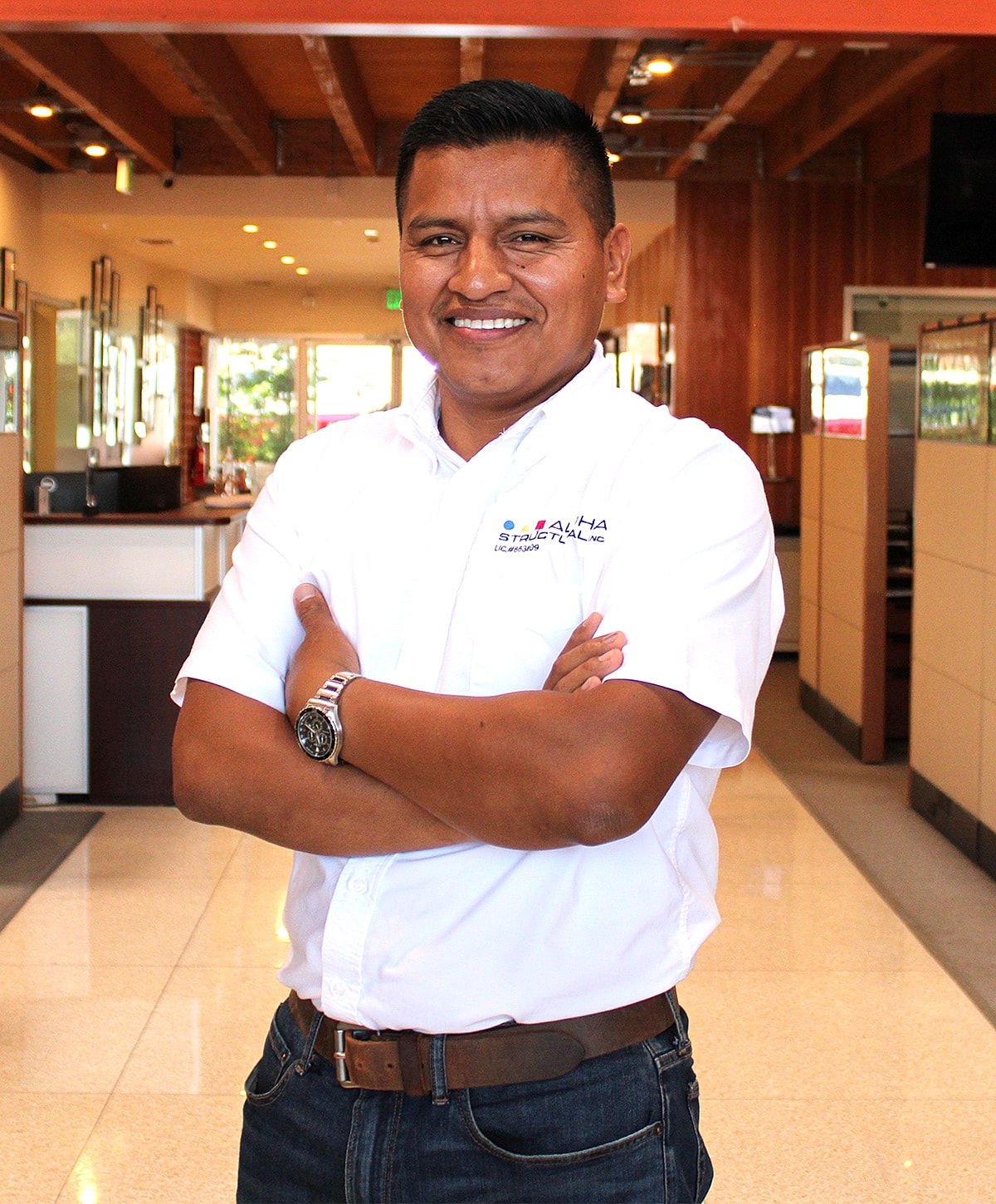 Smiling man in a business setting, arms crossed.