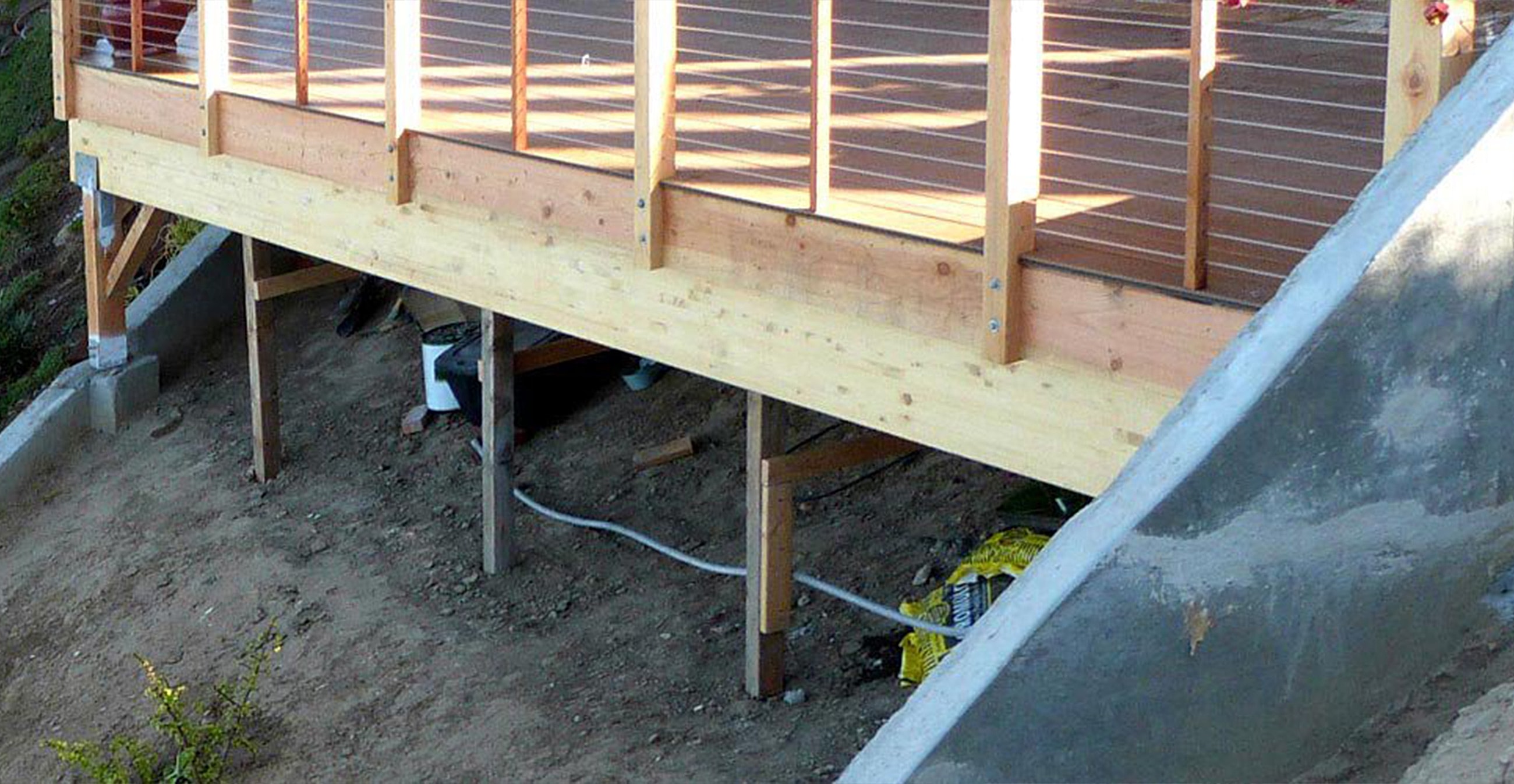 Wooden deck supported by beams and concrete base.