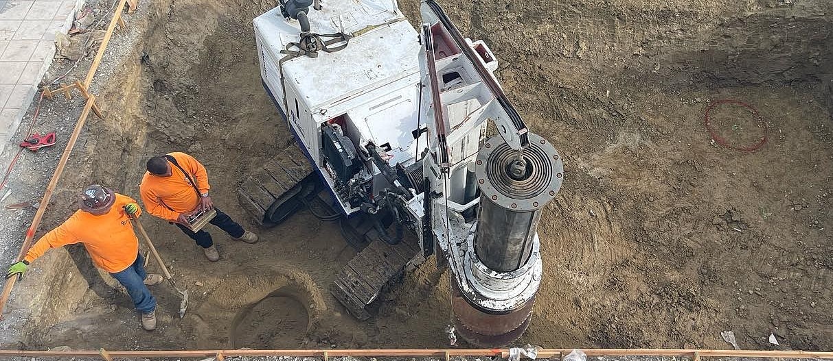 Workers operating machinery in an excavated area.