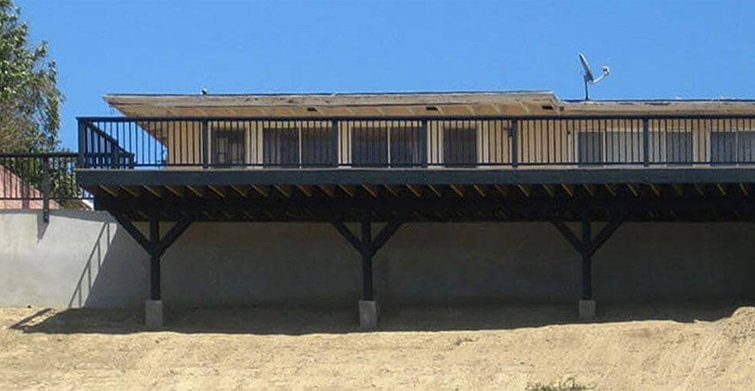 Raised house with balcony and clear blue sky.